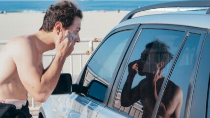man applies sunscreen in car window